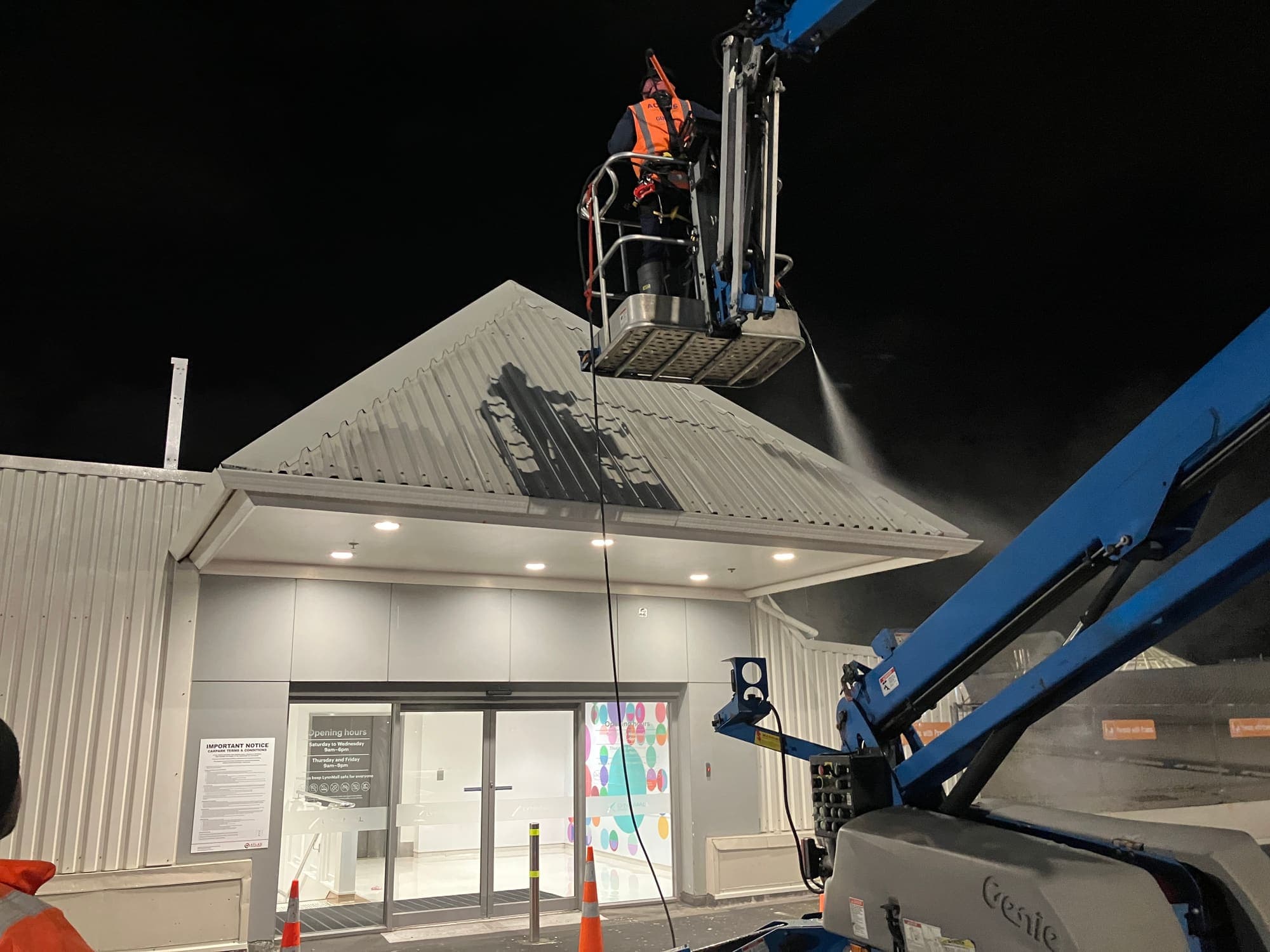 Close view of a technician in high-visibility gear washing the LynnMall roof from the EWP basket