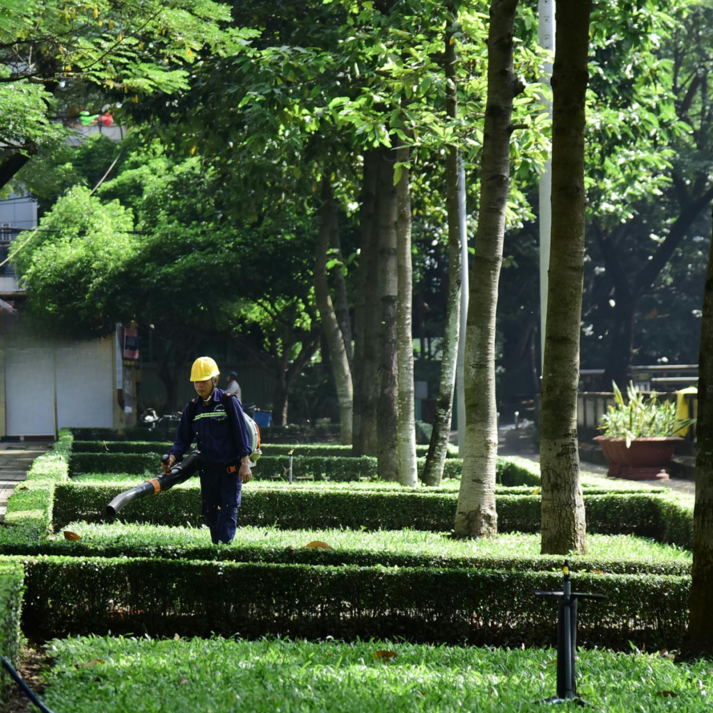 Landscape and garden maintenance: worker using a leaf blower to maintain property, building groundskeeping services.